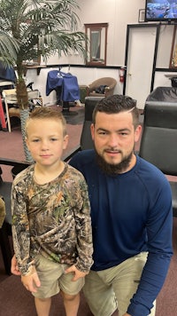 a man and a boy posing for a picture in a barber shop